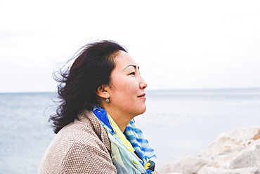 Portrait of the side view of a woman with the ocean in the background, Italy
