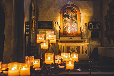 Lit candles and artwork in a cathedral, Italy