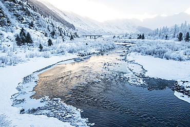 River flowing through a snowy, mountainous landscape at sunrise, Alaska, United States of America