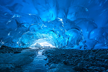 Blue glacial ice is exposed inside an ice cave at the terminus of Mendenhall Glacier, Mendenhall Lake, Tongass National Forest, Alaska, United States of America