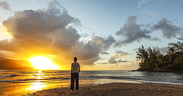 Woman standing on the beach at sunset, Kauai, Hawaii, United States of America