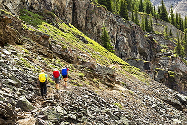 A group of female hikers along a rocky mountain pathway with rock cliffs in the background, British Columbia, Canada