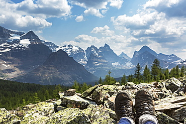 Hiker's boots resting on a rocks with valley and mountain range in the background, British Columbia, Canada