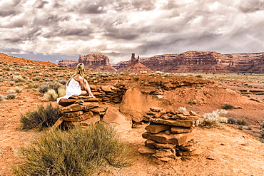 A woman sits on a rock in the Valley of the Gods, Utah, United States of America