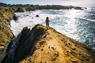 A woman stands looking out along the Russian Gulch Headlands, Mendocino county, California, United States of America