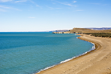 A desert coastline and beach contrast with the blue ocean and sky, Santa Cruz, Argentina