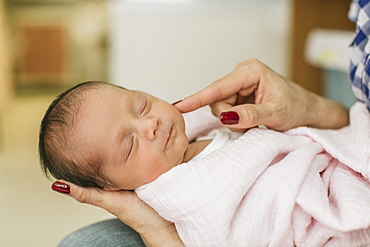 Newborn baby in mother's arms in the Neonatal Intensive Care Unit, Surrey, British Columbia, Canada