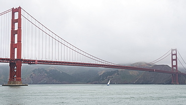 Golden Gate Bridge on a cloudy day with a sailboat on the water below, San Francisco, California, United States of America