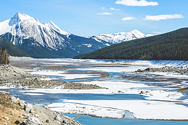 Snow on the lake and snow-capped rugged mountains peaks in Jasper National Park, Alberta, Canada