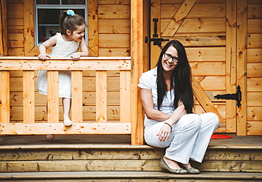 Portrait of a mother and daughter with a wooden playhouse, Alberta, Canada