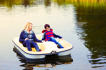 A mother and son taking a ride in a paddle boat on a lake, holding hands and talking together, Edmonton, Alberta, Canada