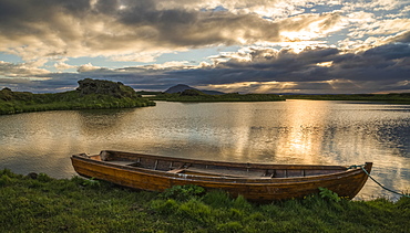 A boat lies in a placid Lake Myvatn, North Iceland at sunset, Iceland