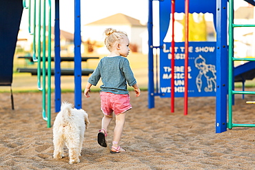 A young girl and her pet dog playing in a playground on a warm fall day, Spruce Grove, Alberta, Canada