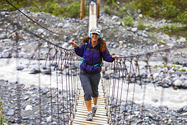 Female hiker crosses a wooden foot bridge on her way to Gulkana Glacier, Alaska, United States of America