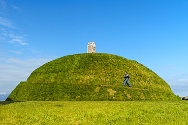 Man walking up Thufa grassy dome with fish drying house on top (art installation by Olof Nordal), Reykjavik, Iceland