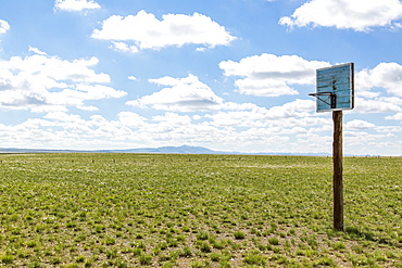 A basketball hoop with backboard in the middle of a grass field in the Gobi desert, Ulaanbaatar, Ulaanbattar, Mongolia