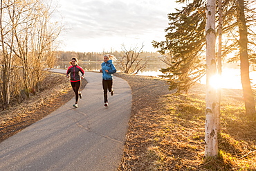 Two young women running on a trail at the water's edge, Anchorage, Alaska, United States of America