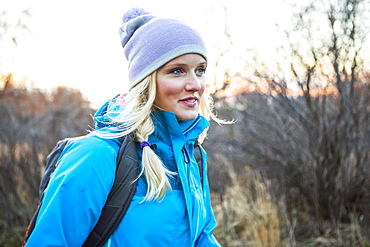 A young women carrying a backpack and walking at sunrise, Anchorage, Alaska, United States of America