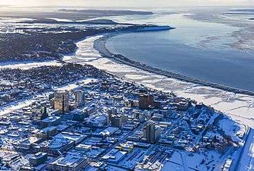 Aerial view of snow covering downtown Anchorage and Cook Inlet at low tide, the Hotel Captain Hook and Conoco Philips buildings in the foreground, Fire Island in the distance, South-central Alaska in winter, Anchorage, Alaska, United States of America