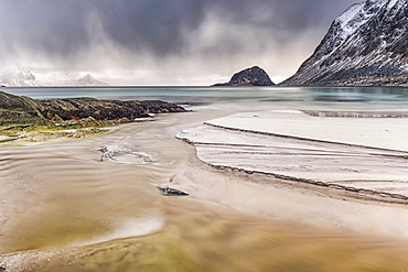 A landscape with rugged mountains and sand along the coastline under a cloudy sky, Nordland, Norway