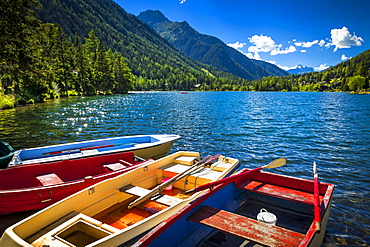 Colourful row boats with Champex Lake surrounded by mountains under blue sky, Alps, Champex, Switzerland