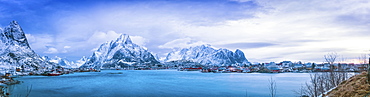 Panoramic of the rugged mountains along the coastline of Norway at sunrise under a blue hue, Svolvar, Lofoten Islands, Nordland, Norway