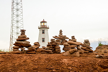 Rocks balanced in piles with a lighthouse in the background, Prince Edward Island, Canada