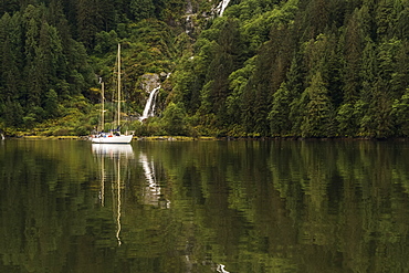 Sailboat in the Great Bear Rainforest with a waterfall along the coast, Hartley Bay, British Columbia, Canada