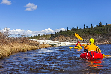 Female packrafters negotiating a tributary of the Charley River with aufeis in summer, Alaska, United States of America