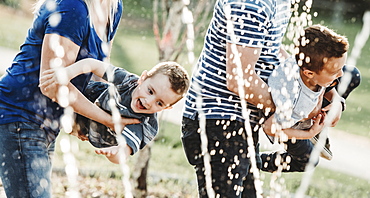 A family with young children playing at a spray park, Edmonton, Alberta, Canada