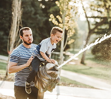 Father and young son at spray park, Edmonton, Alberta, Canada