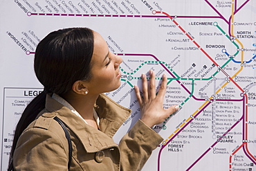 Hispanic woman looking at a route map at a subway station