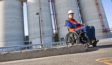 Facilities engineer in wheelchair inspecting outdoor bulk storage tanks