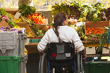 Woman with spinal cord injury in wheelchair shopping at outdoor market