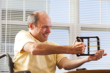 Man with Friedreich's Ataxia with deformed hands using hand strengthening equipment