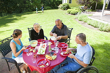 Man with spinal cord injury in wheelchair at family picnic with grandparents included