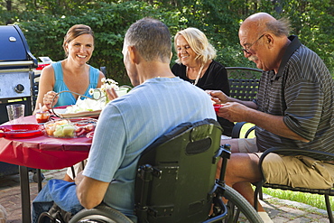 Man with spinal cord injury in wheelchair at family picnic with grandparents included