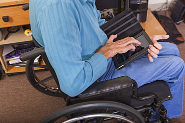 Man with Friedreich's Ataxia in wheelchair using a tablet with deformed hands