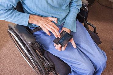 Man with Friedreich's Ataxia in wheelchair using a smartphone with deformed hands