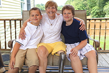 Grandmother with a prosthetic leg with her grandchildren sitting on their outdoor patio