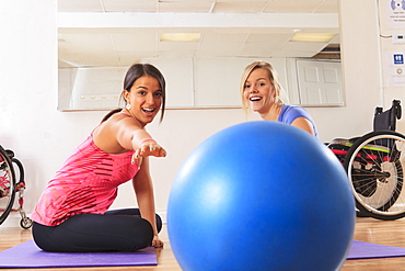 Young women with a spinal cord injuries playing with an exercise ball