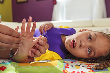 Mother stretching hands of small daughter with Cerebral Palsy