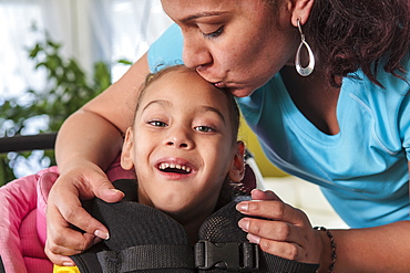 Mother kissing small daughter with Cerebral Palsy