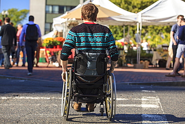 Trendy man with a spinal cord injury in wheelchair at a city outdoor market