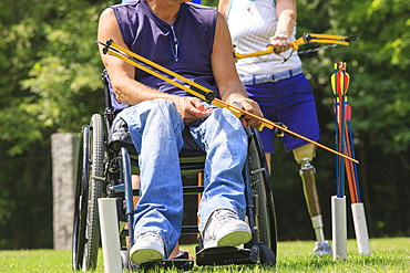 Man with spinal cord injury and woman with prosthetic leg preparing bow and arrow for practice