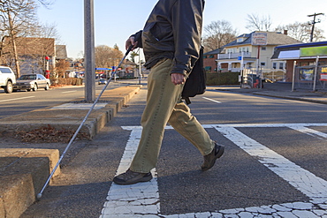 Man with congenital blindness crossing the street using his cane