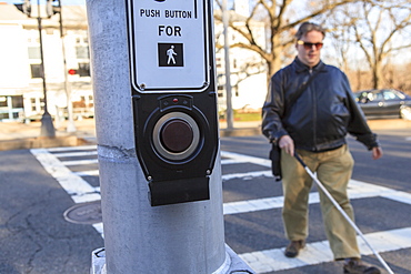 Man with congenital blindness crossing the street using his cane