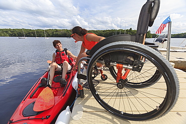 Instructor helping a woman with a Spinal Cord Injury get into a kayak