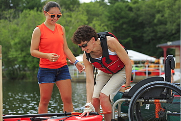 Instructor helping a woman with a Spinal Cord Injury with using a kayak