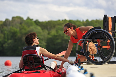 Instructor helping a woman with a Spinal Cord Injury use a kayak